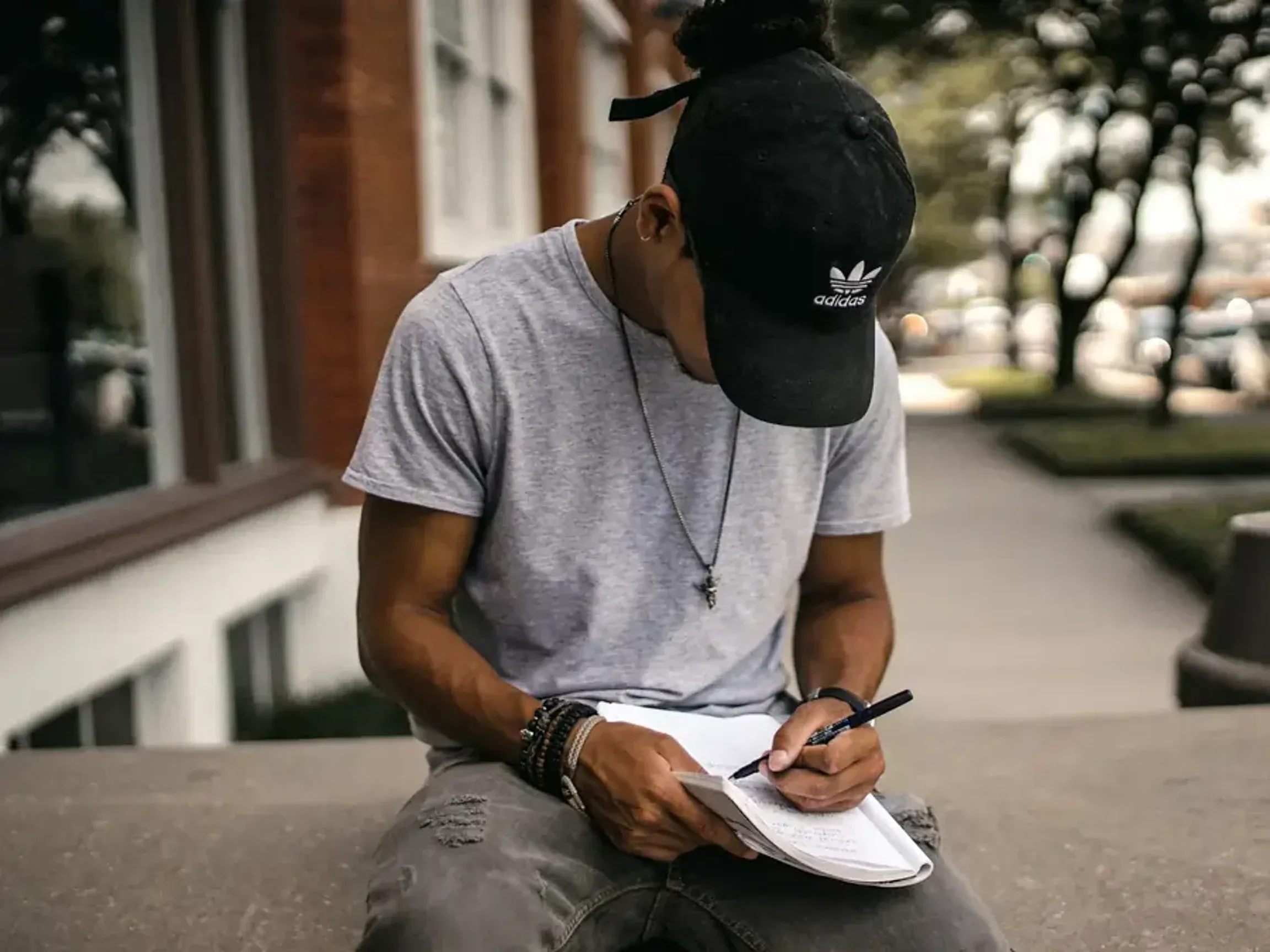 Man sitting outside writing in a notebook.